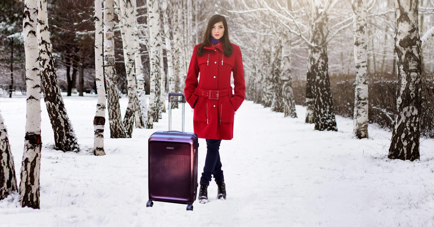 Woman standing in snow with briggs riley purple suitcase